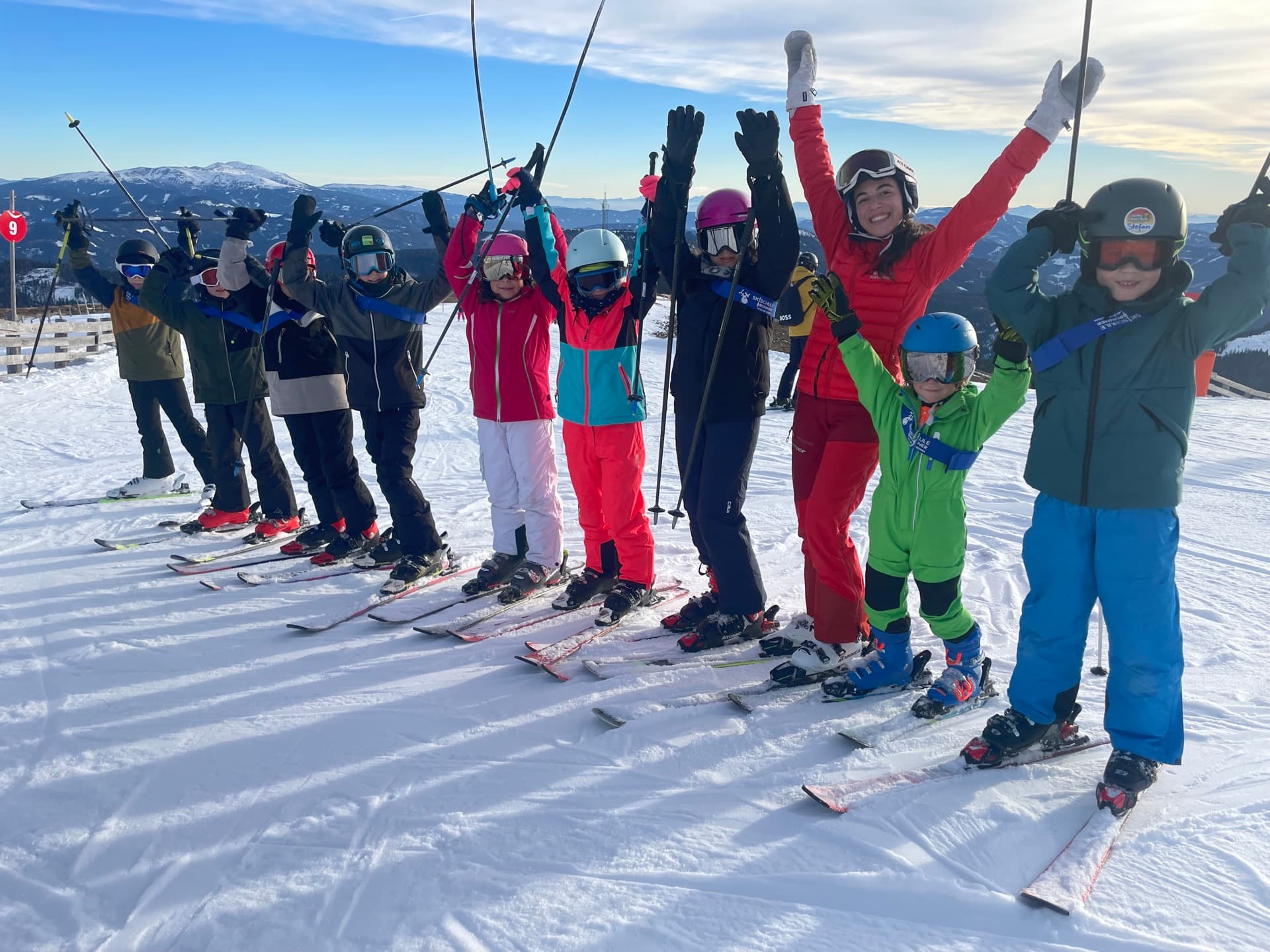 Kindergruppe der Skischule Brunner jubelt mit Skilehrerin auf der Piste