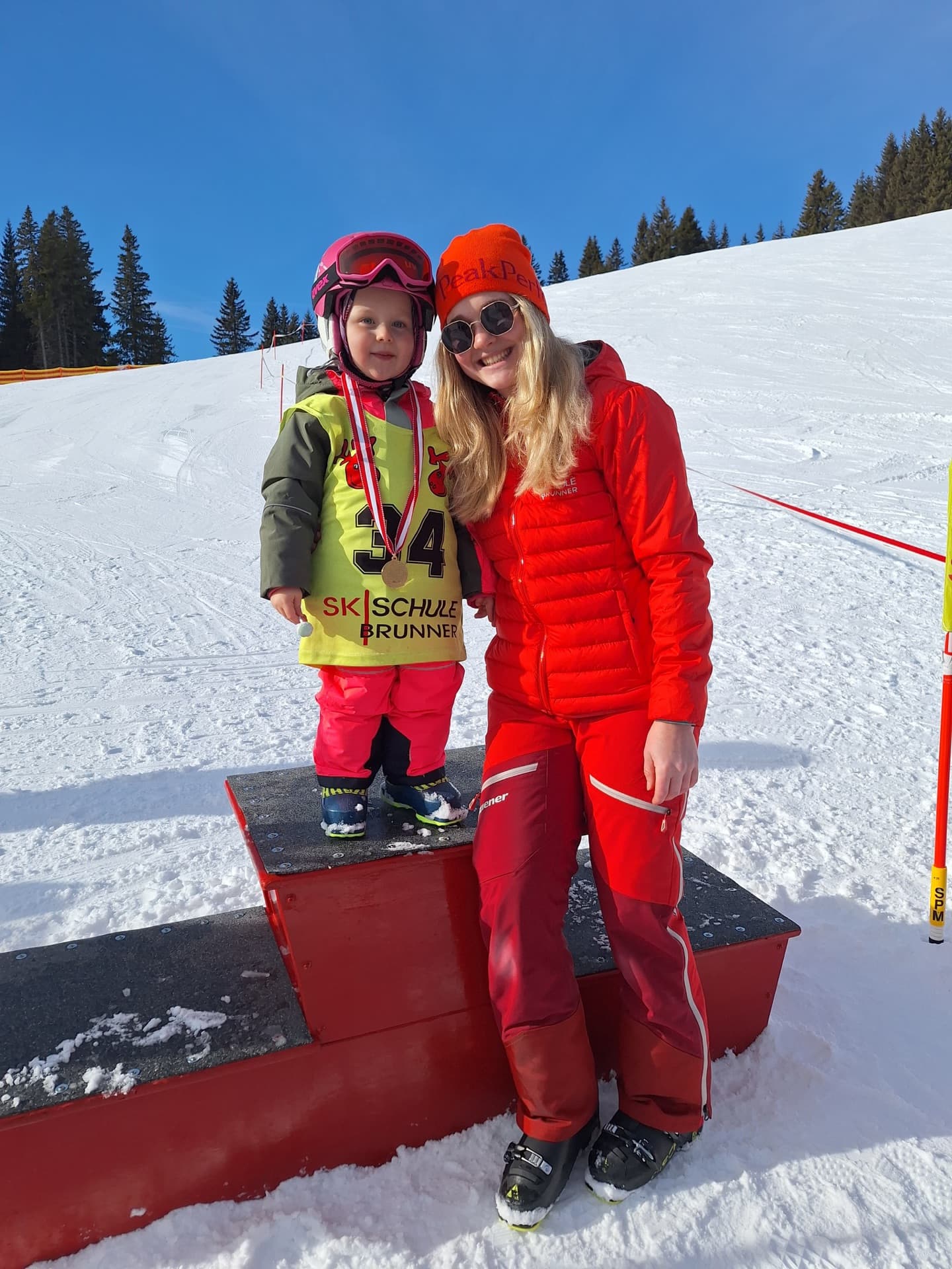 Kleines Kind mit Startnummer und Skilehrerin der Skischule Brunner im Schnee am Lachtal